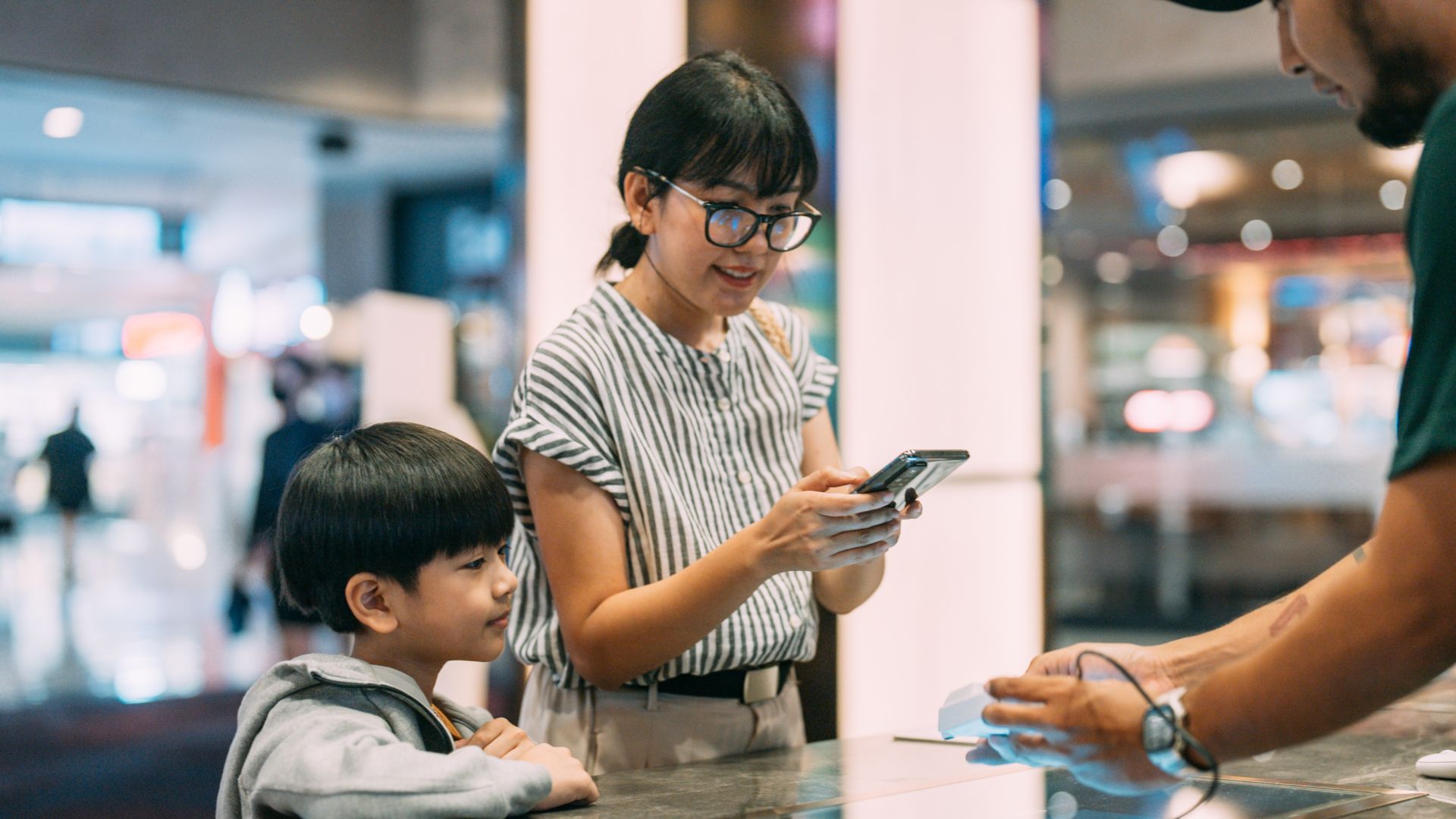 Mom and young son getting tickets on phone
